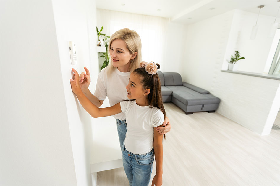 mother and daughter adjusting the thermostat